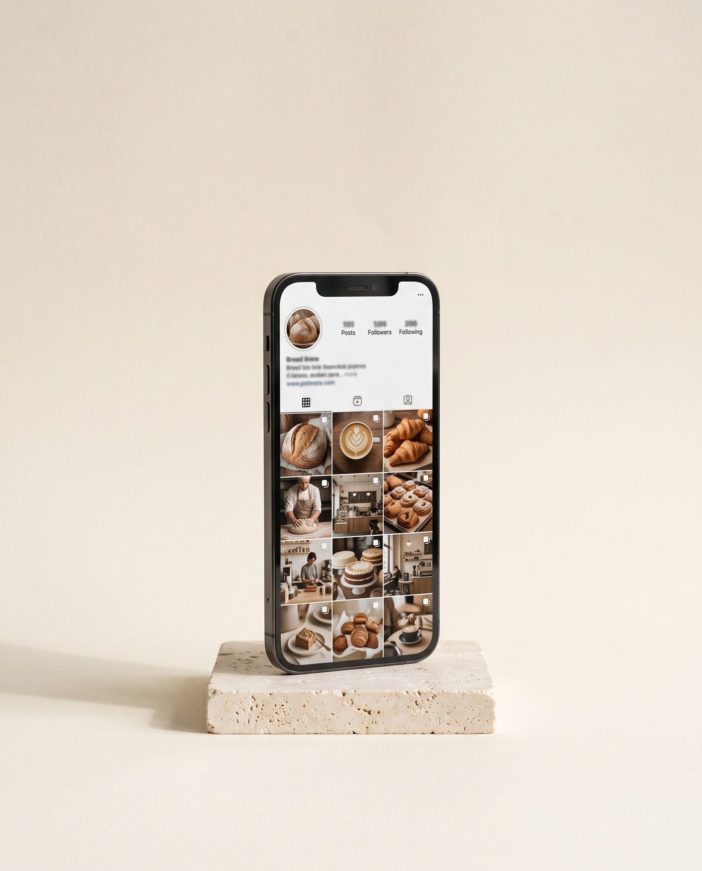 A phone standing on a travertine block, its screen showing a small bakery’s social feed of bread, coffee and the owner at work.